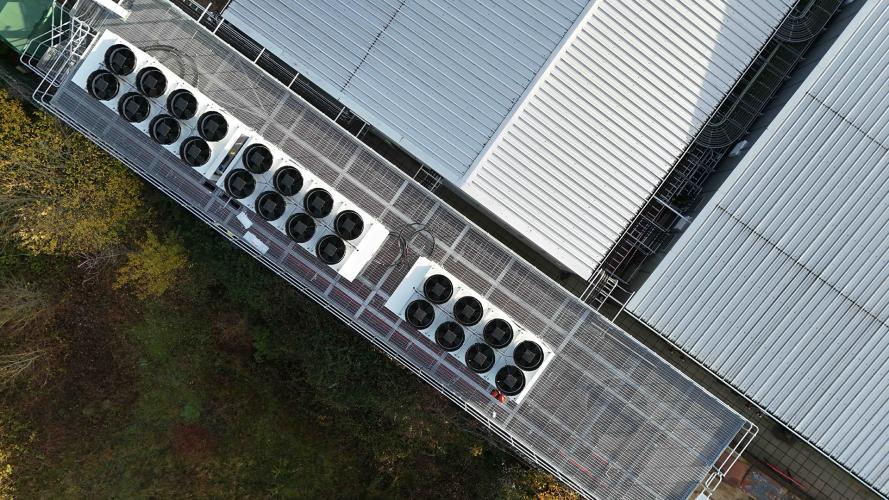 Aerial view of a datacenter with air conditioner compressor fans on the roof of the building