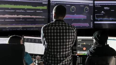 Individuals monitoring computer screens displaying data