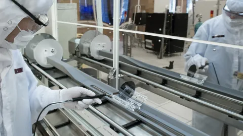 Researcher in protective gear working at a machine