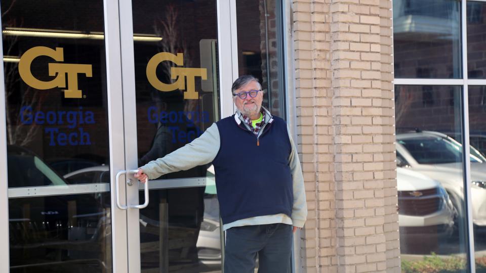A man standing in front of glass double doors with the Georgia Tech logo.
